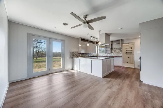 a large kitchen with stainless steel appliances granite countertop a stove a sink dishwasher and a large refrigerator with wooden floor