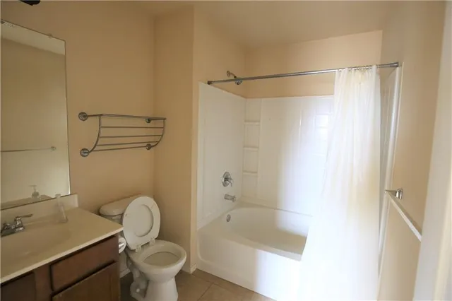 a bathroom with a granite countertop bathtub shower sink vanity and toilet