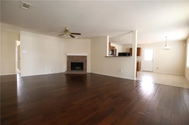 an empty room with wooden floor fireplace and windows