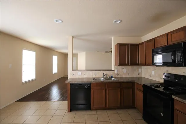 a kitchen with granite countertop a sink a stove and cabinets