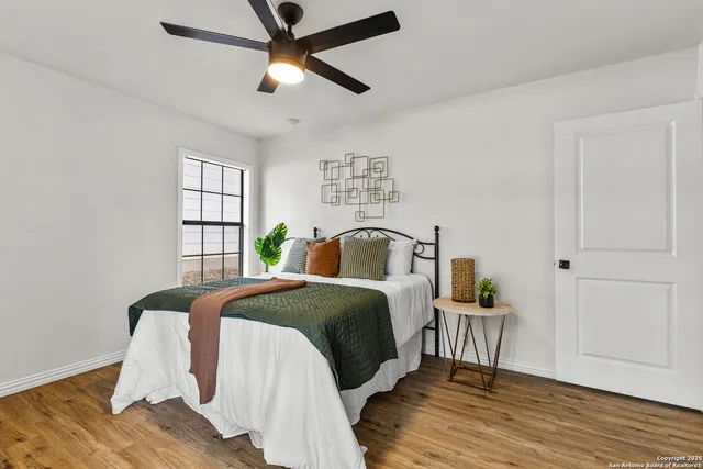 a spacious bedroom with a bed a dresser and wooden floor