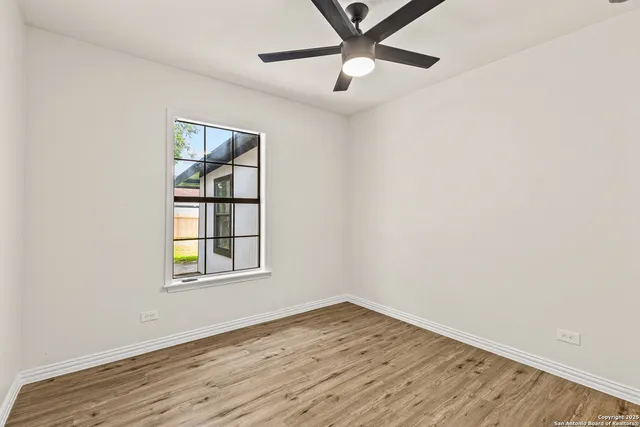 an empty room with wooden floor chandelier and windows