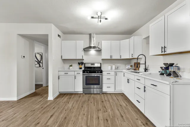 a kitchen with granite countertop a stove and white cabinets