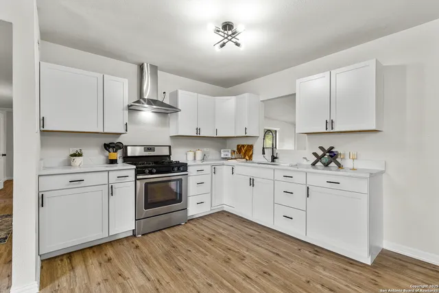 a kitchen with stainless steel appliances granite countertop a stove a sink and white cabinets