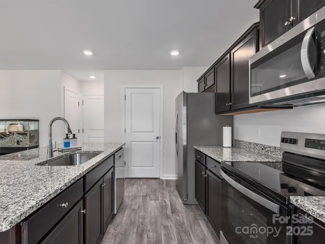 a kitchen with stainless steel appliances granite countertop a sink stove and refrigerator