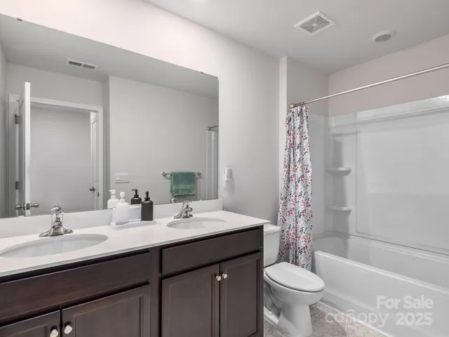 a bathroom with a double vanity sink toilet mirror and bathtub
