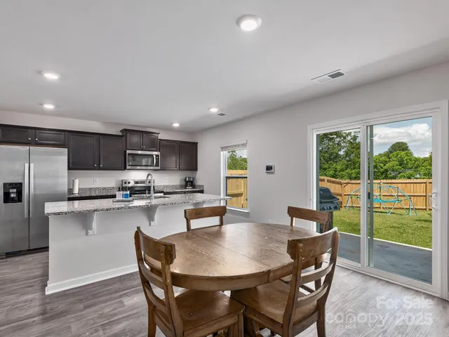 a dining room with stainless steel appliances granite countertop a stove a refrigerator a kitchen with a dining table and chairs