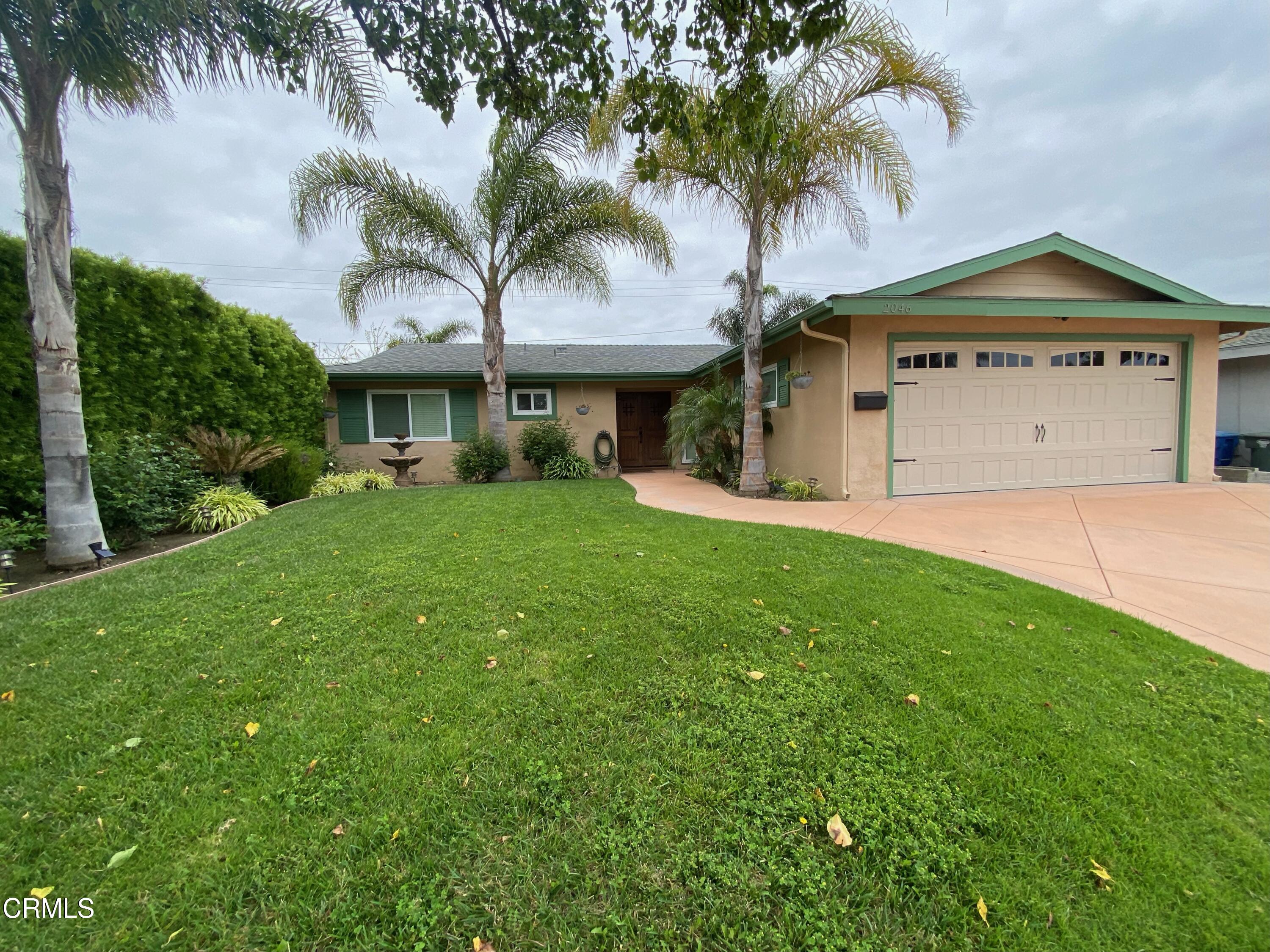 a view of a house with a yard and palm trees