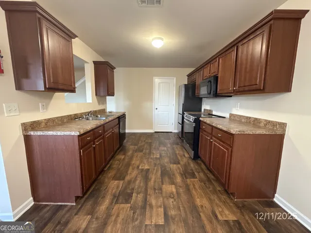 a kitchen with stainless steel appliances granite countertop wooden cabinets a stove top oven a sink and dishwasher