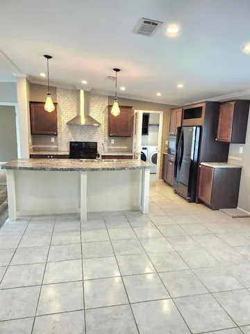 a kitchen with granite countertop a refrigerator and a stove top oven