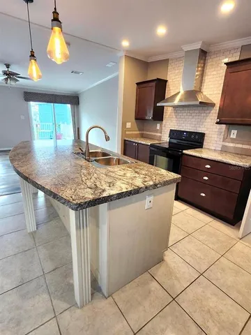 a kitchen with kitchen island granite countertop a stove top oven a sink dishwasher a dining table and chairs with wooden floor