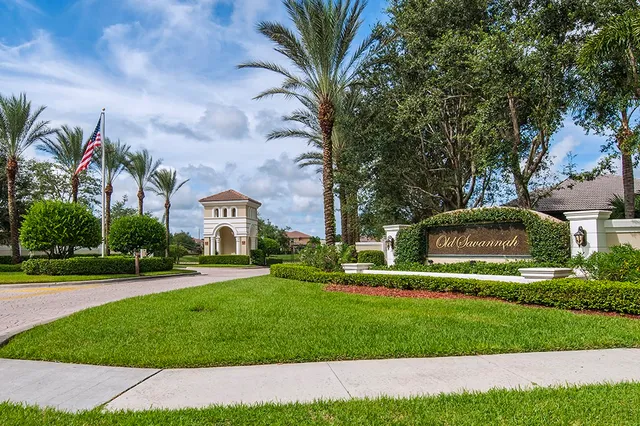a view of a white house with a big yard and potted plants and trees