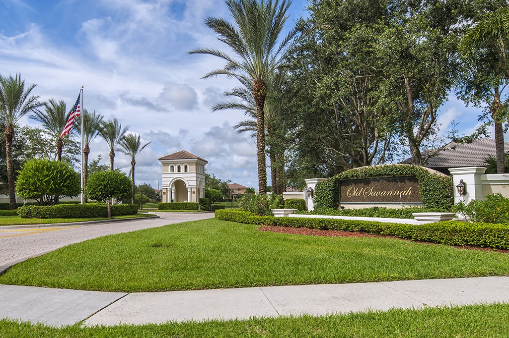 a view of a white house with a big yard and potted plants and trees