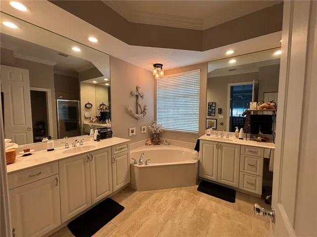 a large white bathroom with a double vanity sink a large mirror and a bathtub