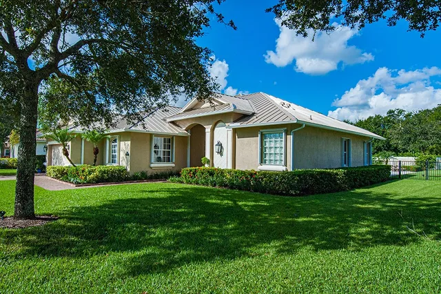 a view of a house with a big yard potted plants and large tree