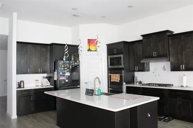 a kitchen with granite countertop a refrigerator a stove and wooden cabinets