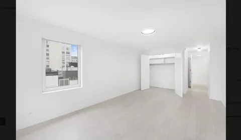 an empty room with a window and a bathroom