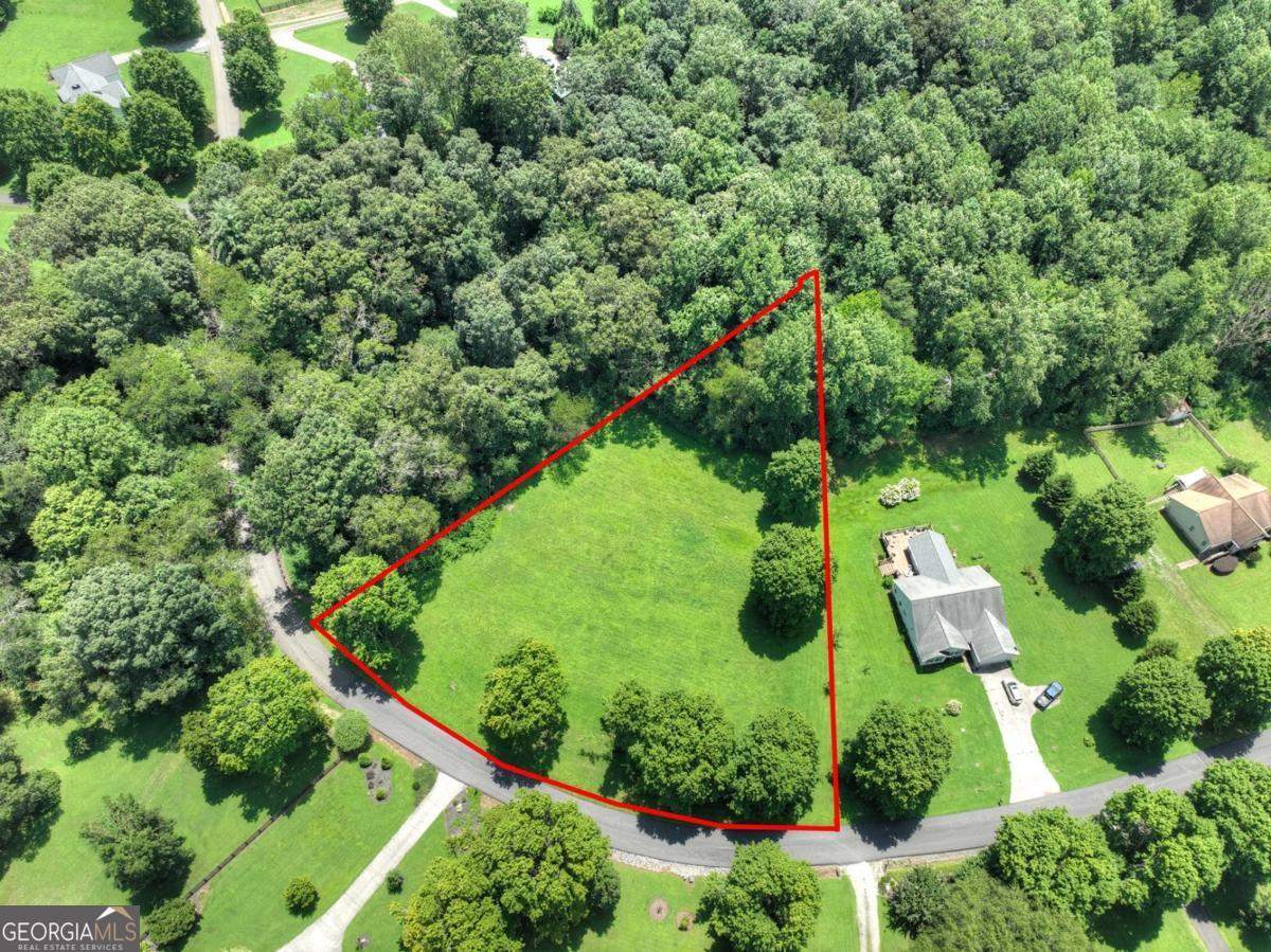 an aerial view of residential house with outdoor space and trees all around