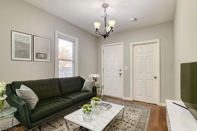 a living room with furniture a chandelier and a flat screen tv