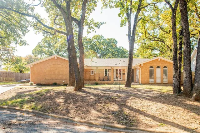 a view of a house with a large tree and wooden fence