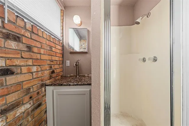 a bathroom with a granite countertop shower a sink and a mirror