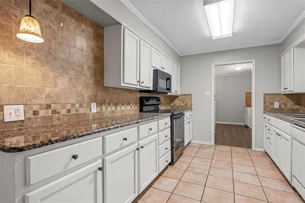 a kitchen with granite countertop white cabinets and stainless steel appliances