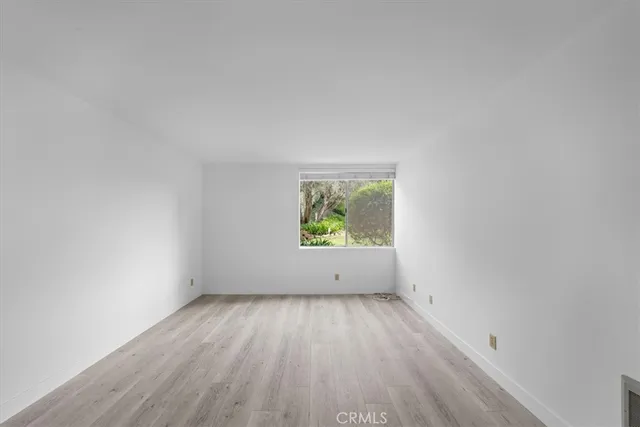 an empty room with wooden floor and window