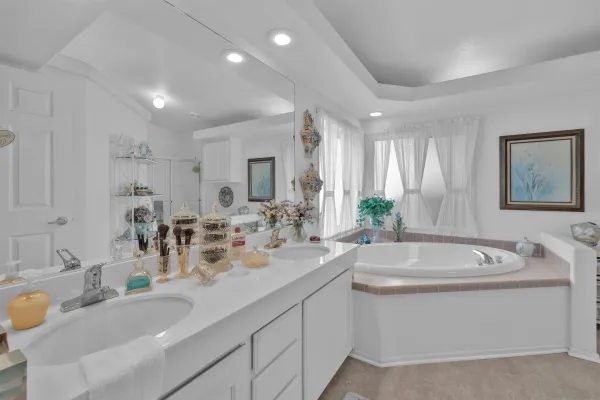 a bathroom with a sink double vanity granite tub and a mirror