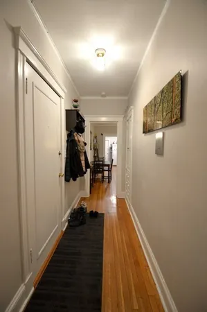 a hallway with wooden floor shoes and staircase
