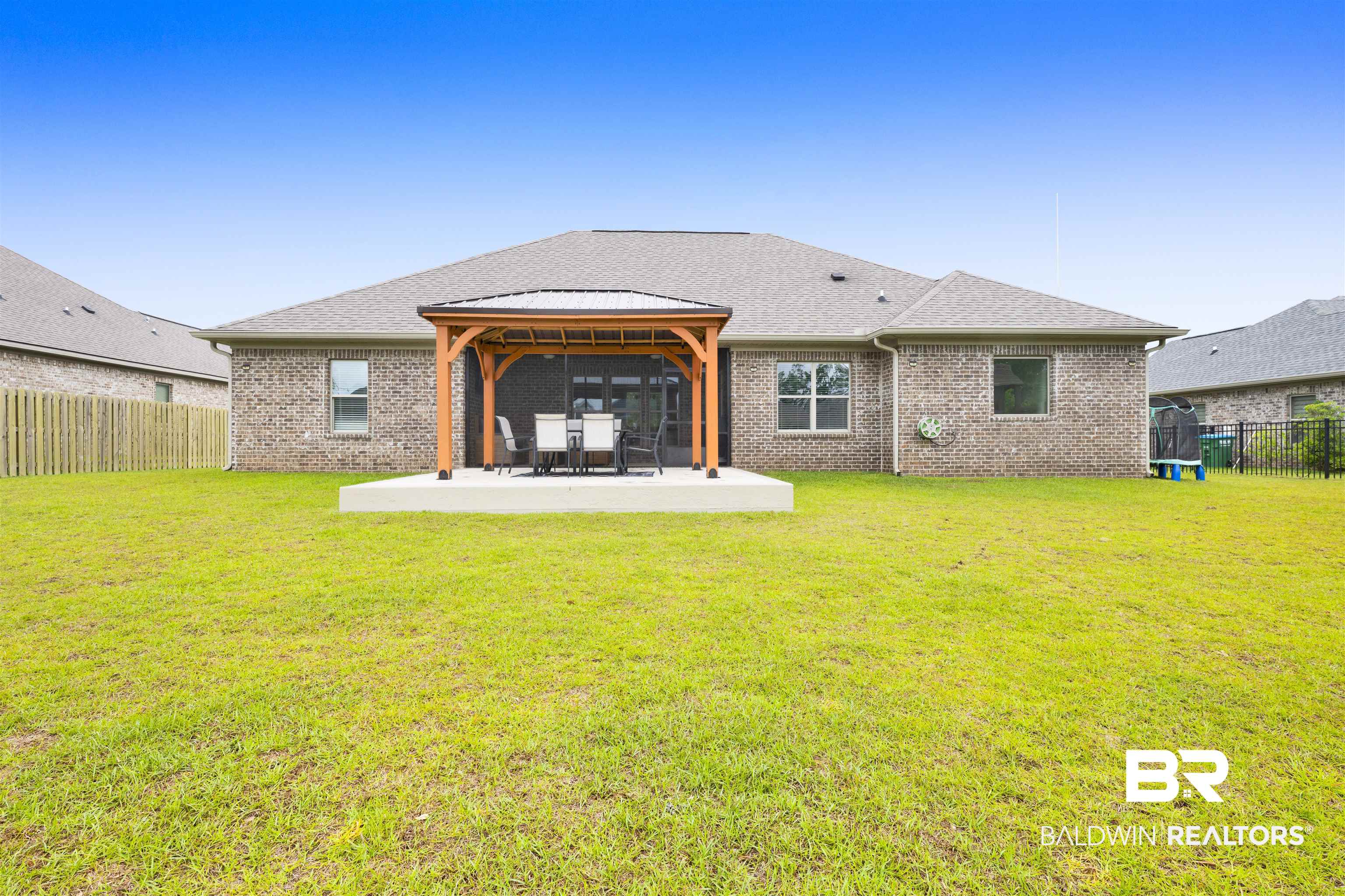 12672 Squirrel Drive Daphne, AL 36527 - Photo 41 of 49 Spacious backyard featuring a large concrete patio, a wooden pergola, brick exterior, and a privacy fence