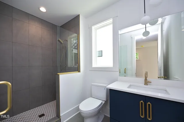 a bathroom with a sink a toilet a mirror and shower