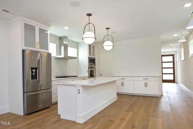 a kitchen with a refrigerator a sink dishwasher and a stove with wooden floor