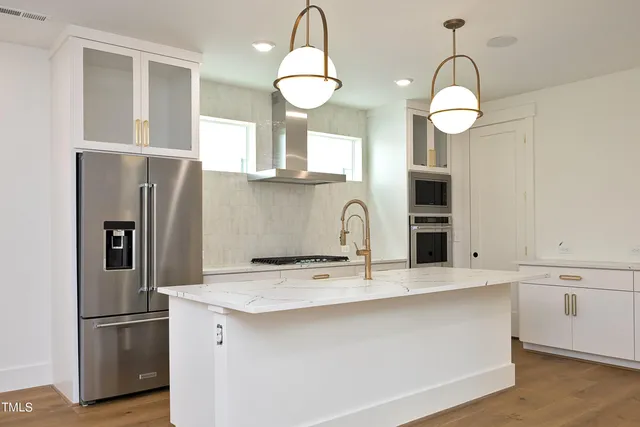 a kitchen with stainless steel appliances a refrigerator a sink a stove and cabinets