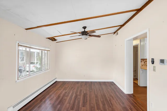 a view of an empty room with wooden floor and a window