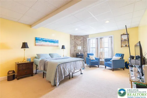 a spacious bedroom with a bed a couch and a flat tv screen next to a window