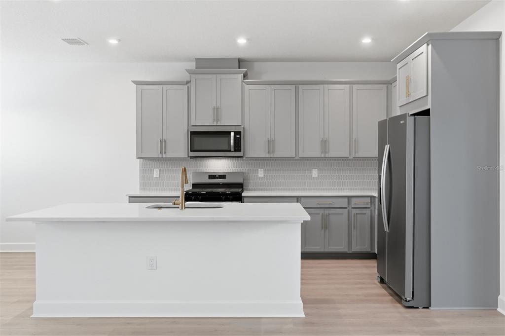1859 Seawall Way Celebration, FL 34747 - Photo 4 of 25 a kitchen with stainless steel appliances a refrigerator stove microwave and sink