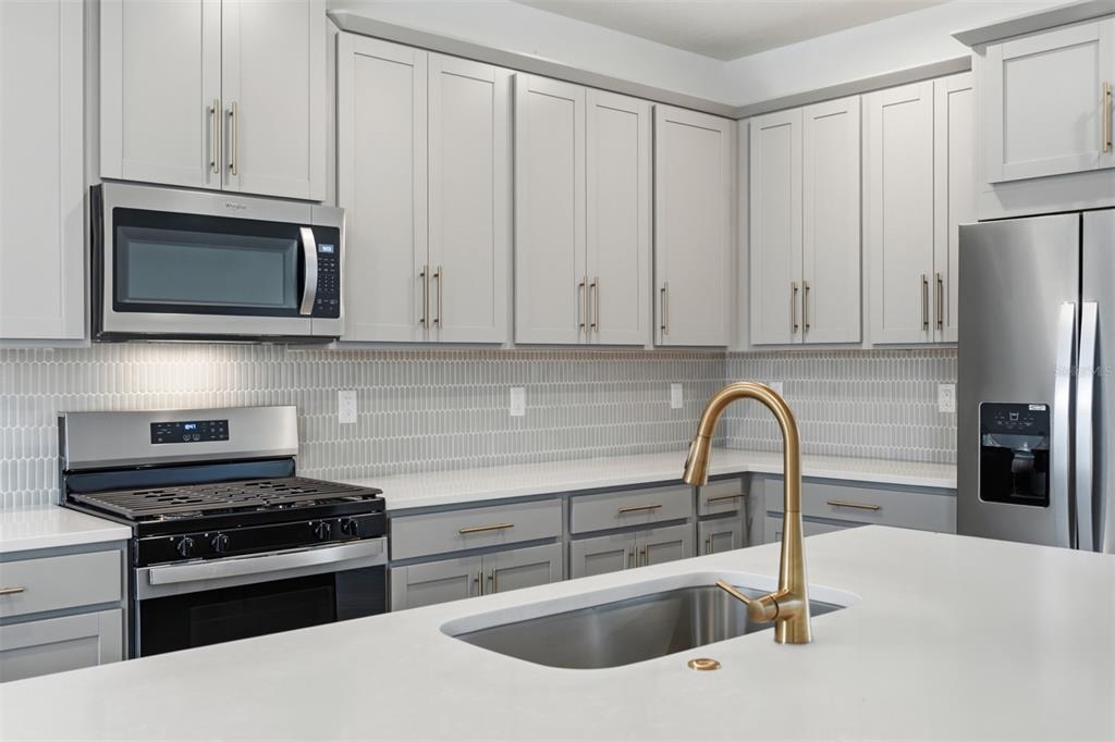 1859 Seawall Way Celebration, FL 34747 - Photo 5 of 25 a kitchen with granite countertop a stove and a microwave
