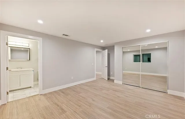 an empty room with wooden floor and mirror