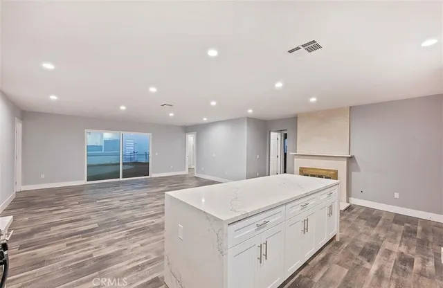 a large white kitchen with wooden floor and large window