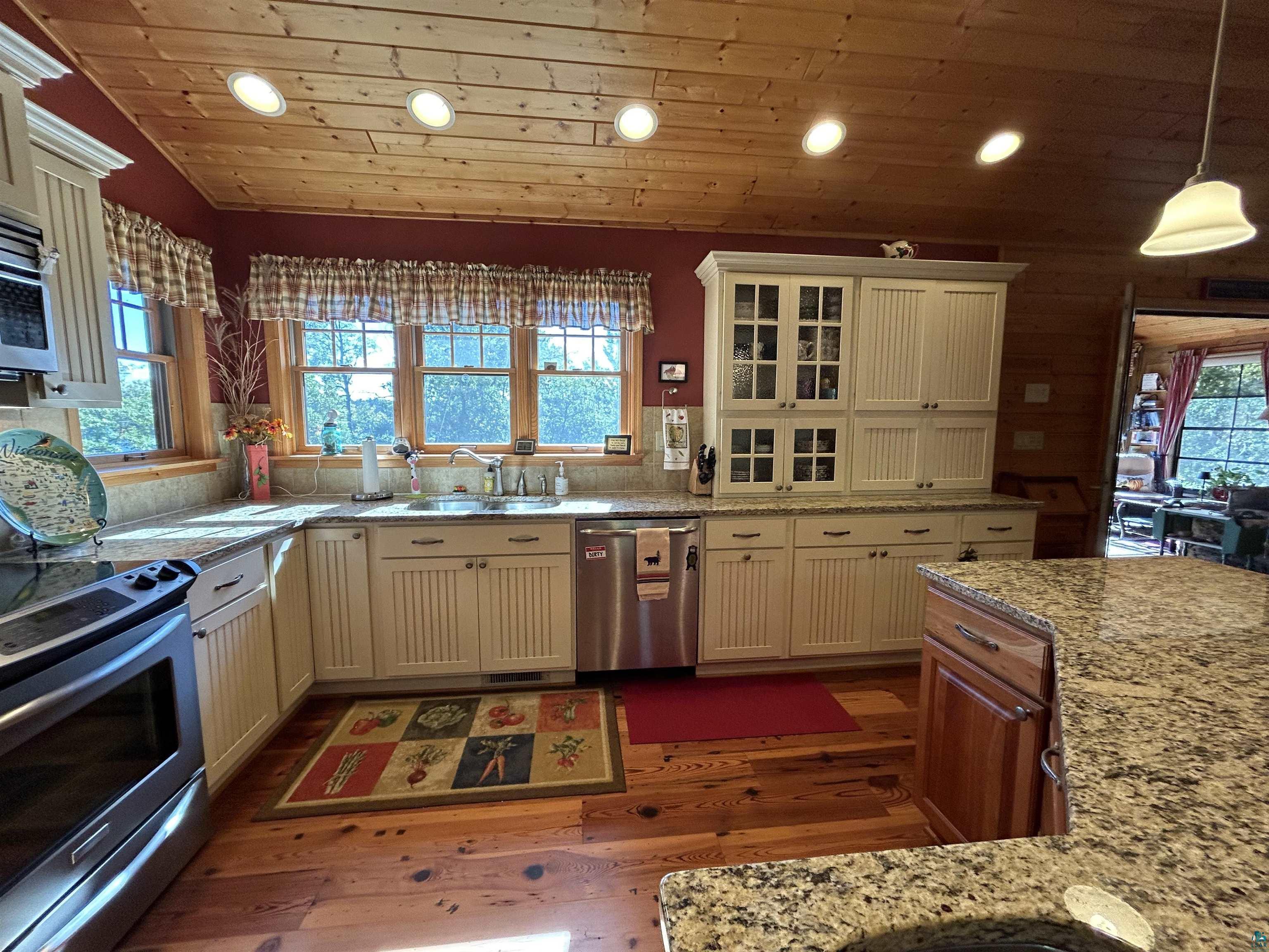 10115 Island Lake Road Solon Springs, WI 54873 - Photo 21 of 56 Kitchen featuring appliances with stainless steel finishes, recessed lighting, dark wood-style floors, glass insert cabinets, and wooden ceiling