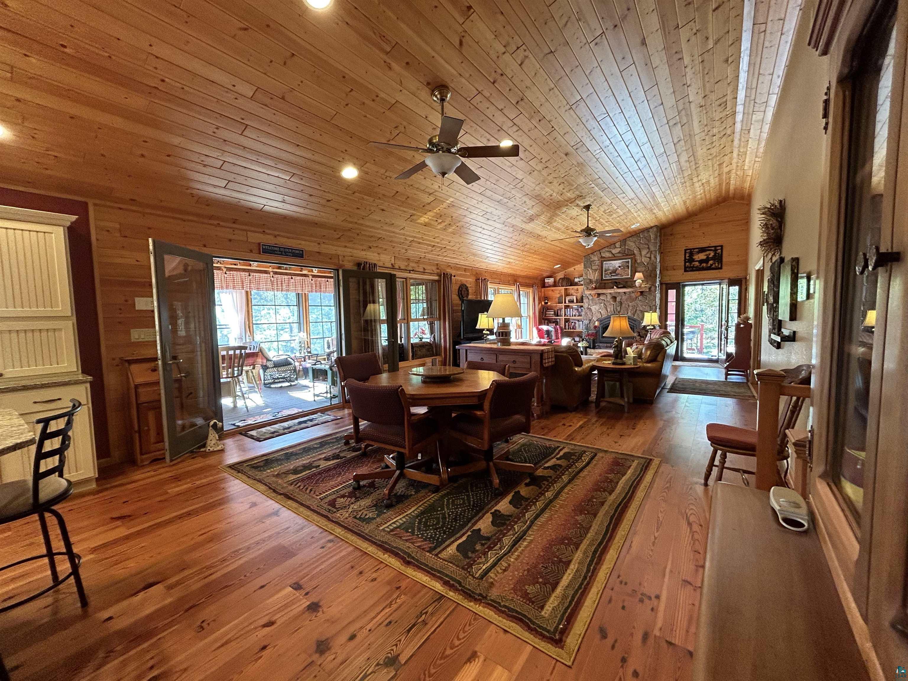 10115 Island Lake Road Solon Springs, WI 54873 - Photo 22 of 56 Dining room featuring plenty of natural light, wooden walls, a ceiling fan, lofted ceiling, and hardwood / wood-style floors