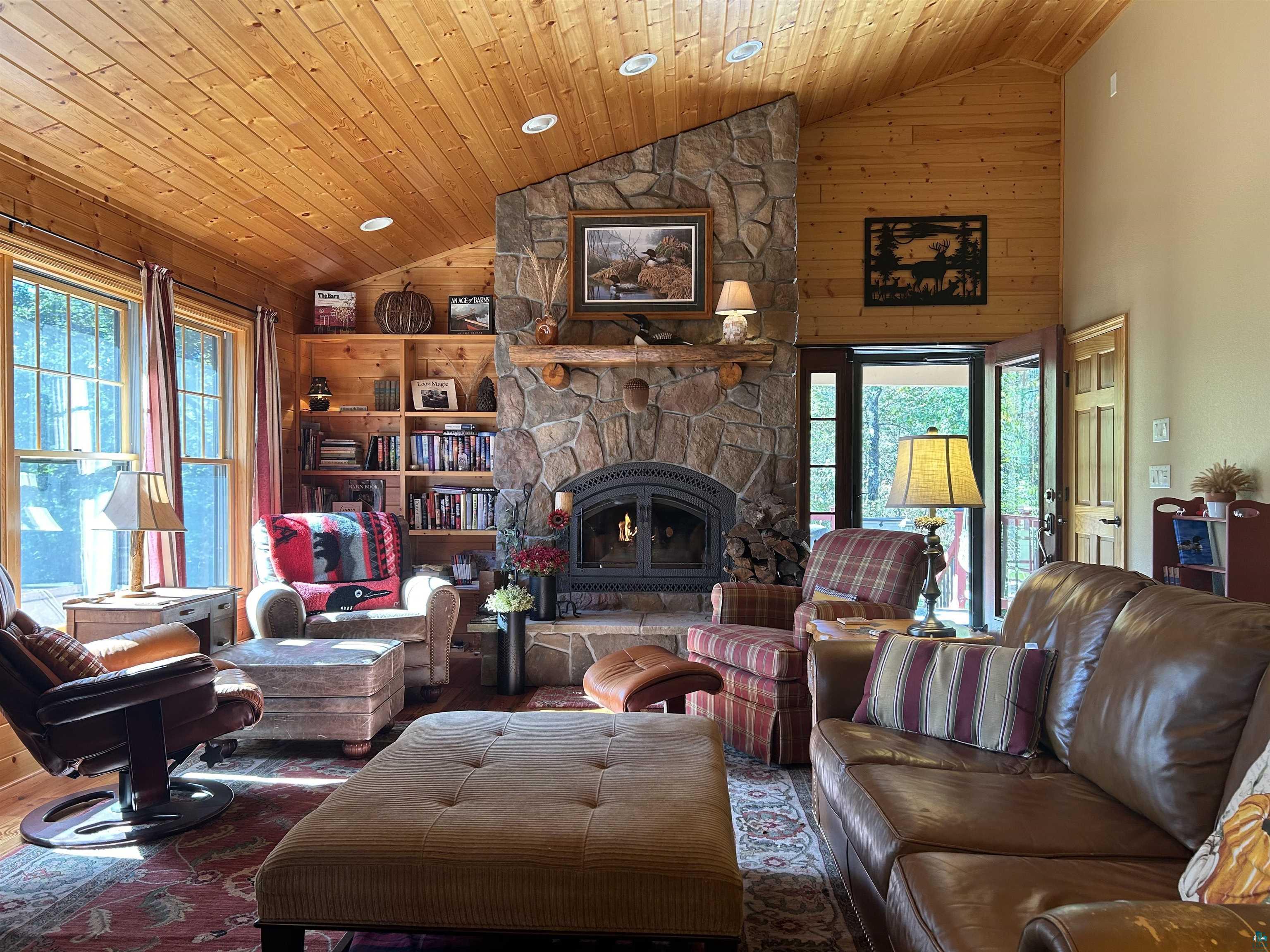 10115 Island Lake Road Solon Springs, WI 54873 - Photo 23 of 56 Living area with wooden walls, high vaulted ceiling, wood ceiling, a stone fireplace, and wood finished floors