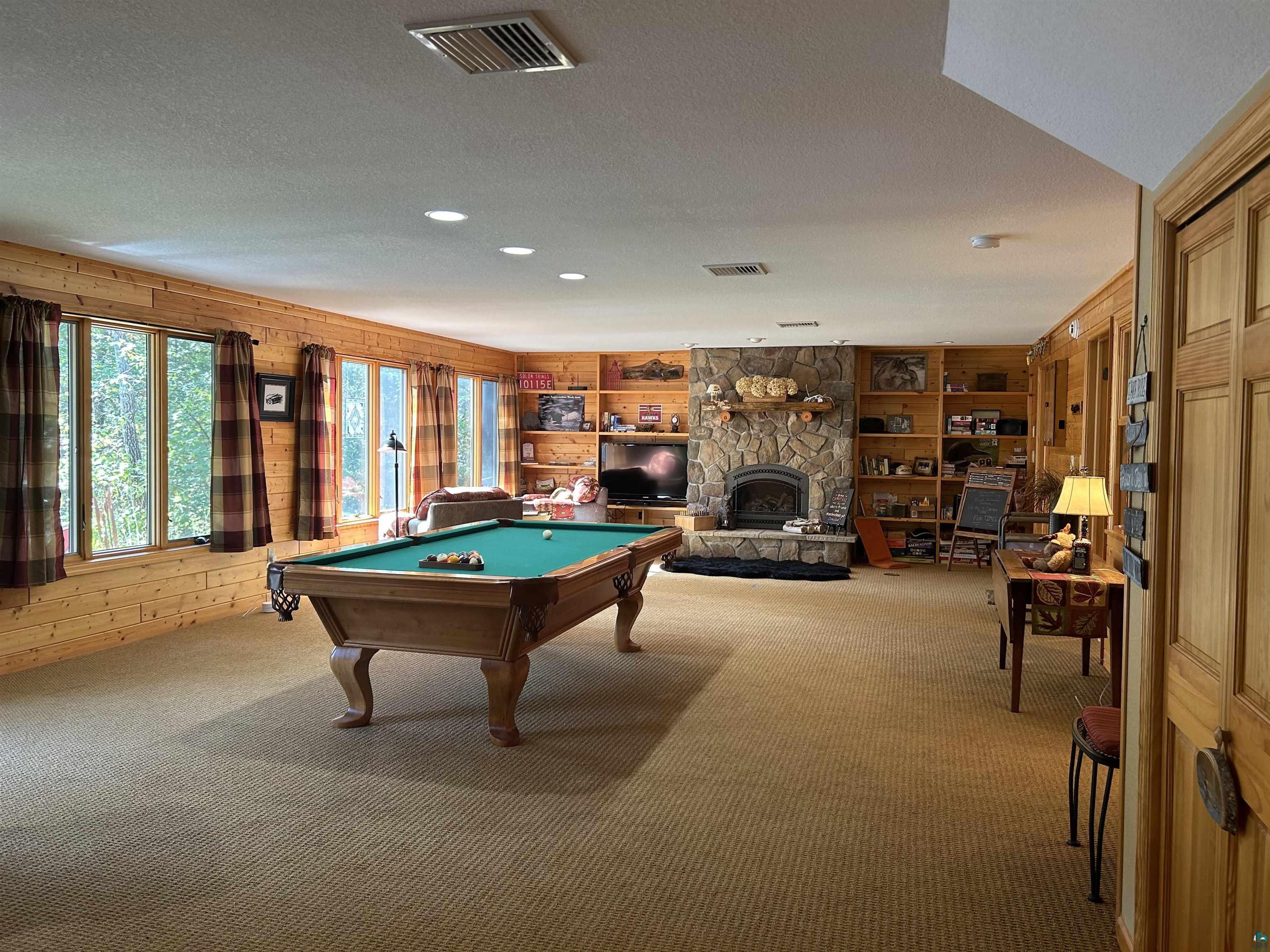 10115 Island Lake Road Solon Springs, WI 54873 - Photo 32 of 56 Recreation room with carpet floors, pool table, wood walls, a stone fireplace, and a textured ceiling