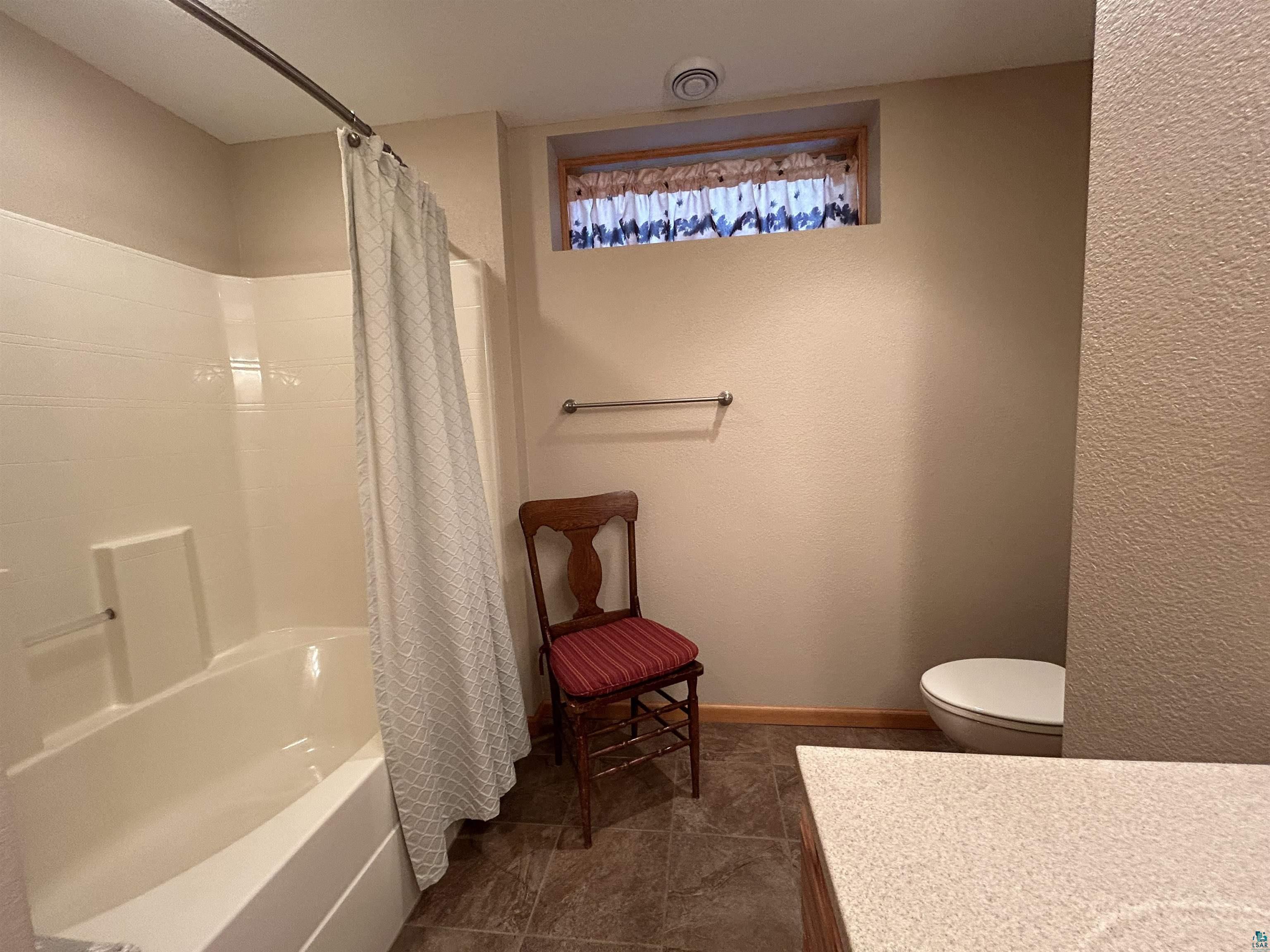 10115 Island Lake Road Solon Springs, WI 54873 - Photo 38 of 56 Bathroom featuring vanity, shower / tub combo with curtain, baseboards, toilet, and tile patterned flooring