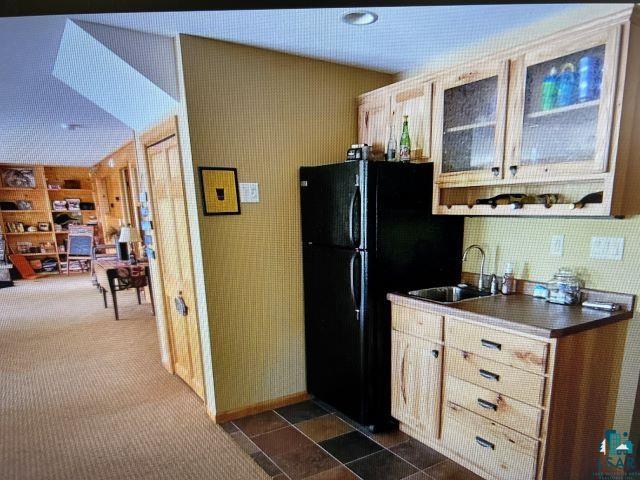 10115 Island Lake Road Solon Springs, WI 54873 - Photo 40 of 56 Kitchen with a sink, dark countertops, freestanding refrigerator, and dark colored carpet