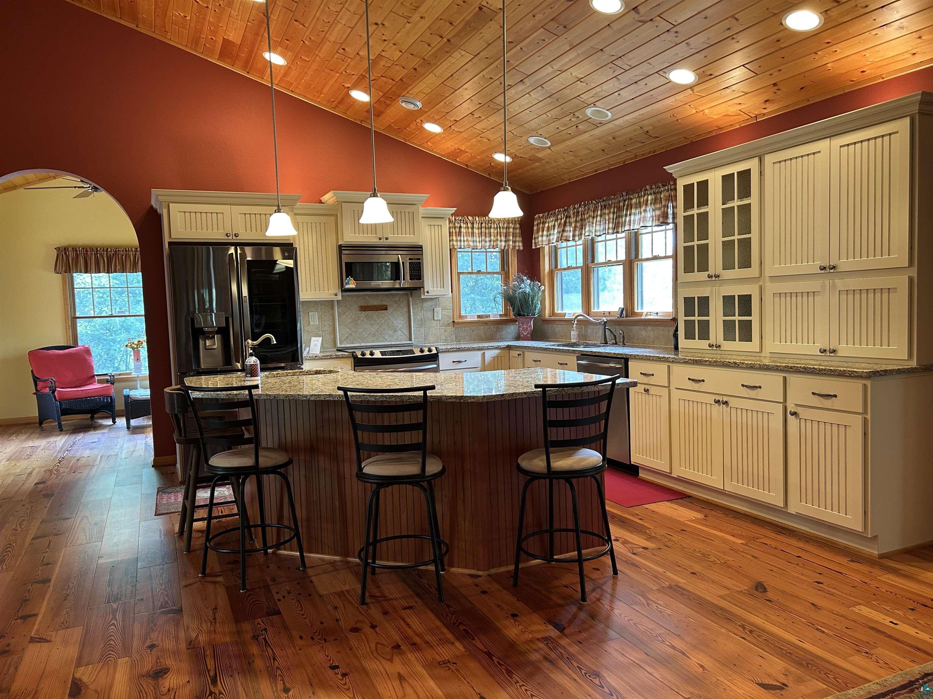 10115 Island Lake Road Solon Springs, WI 54873 - Photo 42 of 56 Kitchen featuring appliances with stainless steel finishes, wood ceiling, dark wood finished floors, a center island, and arched walkways