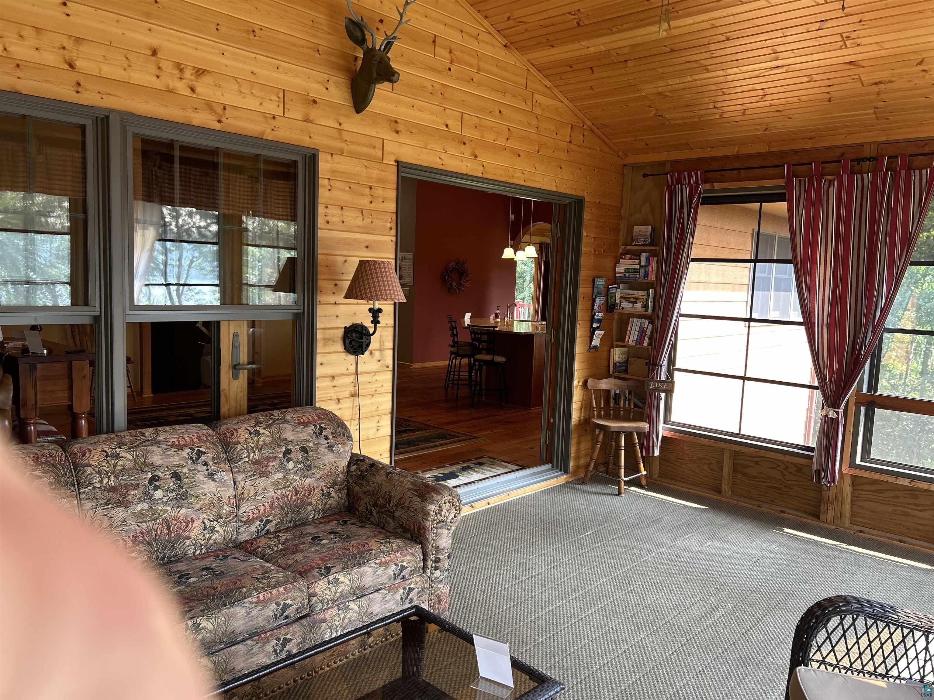 10115 Island Lake Road Solon Springs, WI 54873 - Photo 52 of 56 Living area with lofted ceiling, wood walls, plenty of natural light, carpet floors, and wood ceiling