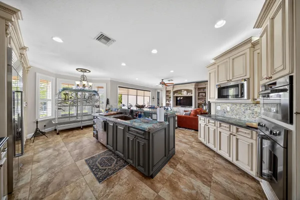a kitchen with stainless steel appliances kitchen island granite countertop a table chairs sink and cabinets