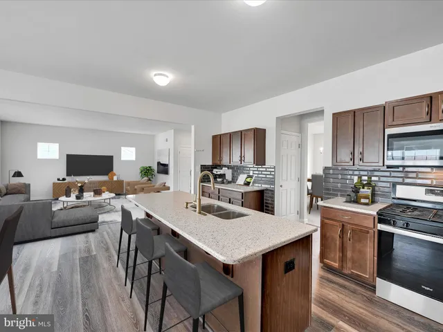 a kitchen with a stove a refrigerator and white cabinets with wooden floor