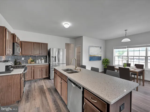 a kitchen with a stove a refrigerator and a dining table with wooden floor